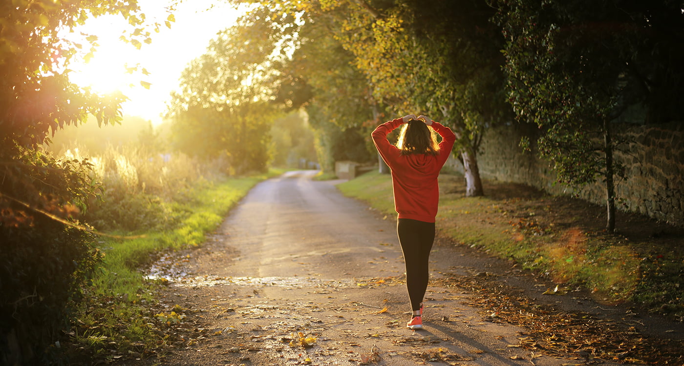 woman walking on a trail with her hands on her head